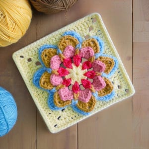 May include: A square, crocheted flower motif in shades of yellow, pink, blue, and brown. The central flower is pink and yellow, surrounded by layers of petals in blue, brown, and pink. The background is a light yellow square with small holes.