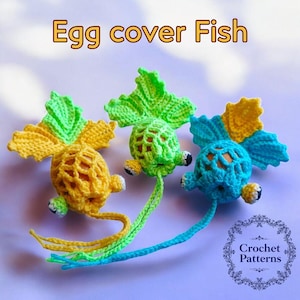 May include: Three crocheted fish egg covers in yellow, green, and blue. The fish have crocheted fins and tails. The fish are designed to hold an egg.