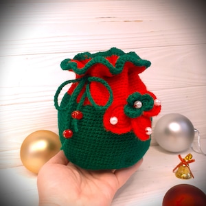 K&ouml;nnte beinhalten: Ein gr&uuml;ner und roter Weihnachtsstrumpf aus H&auml;kelarbeit mit wei&szlig;en Perlenverzierungen und roten Perlen. Der Strumpf ist mit einer roten und gr&uuml;nen Blume verziert.