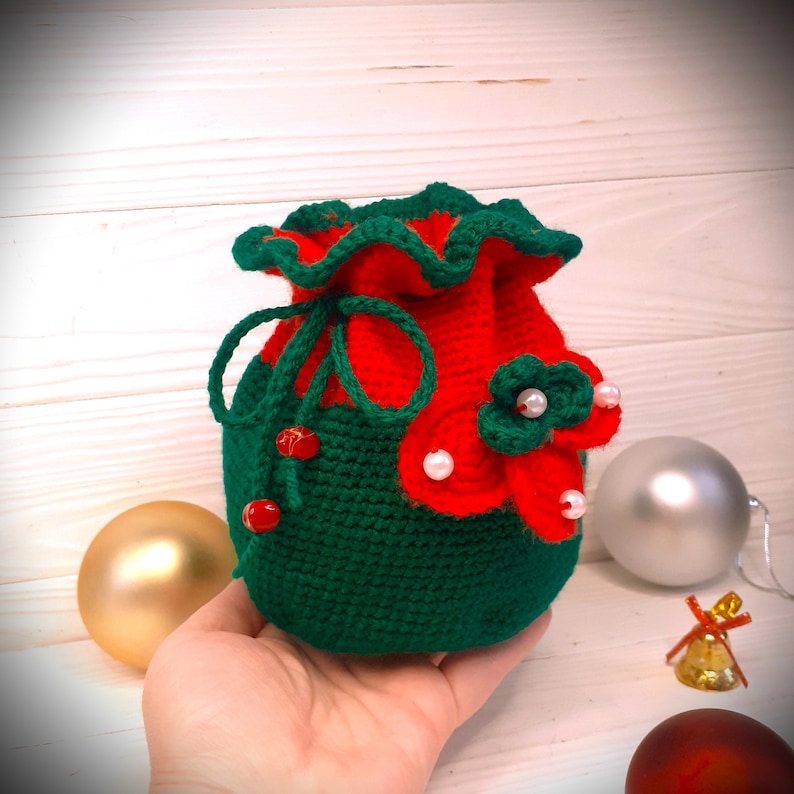 K&ouml;nnte beinhalten: Ein gr&uuml;ner und roter Weihnachtsstrumpf aus H&auml;kelarbeit mit wei&szlig;en Perlenverzierungen und roten Perlen. Der Strumpf ist mit einer roten und gr&uuml;nen Blume verziert.