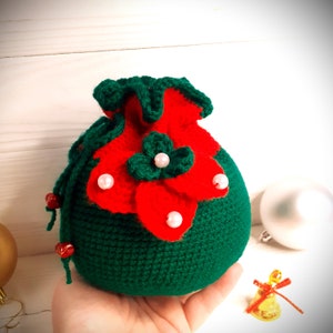 K&ouml;nnte beinhalten: Ein gr&uuml;ner Weihnachtsstrumpf aus H&auml;kelarbeit mit rotem Blumendesign und wei&szlig;en Perlenakzenten.