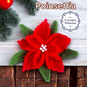 以下が含まれることがあります： 緑の葉と真珠のアクセントが付いた、手作りの赤いポインセチアの花。画像には「Poinsettia」と「Crochet Patterns」の文字が含まれています。花は、クリスマスの装飾が施された白い木の背景に配置されています。
