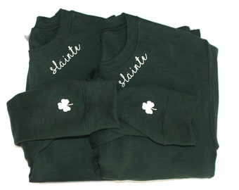 May include: Two dark green sweatshirts with white embroidered shamrocks and the word "Slainte" on the front.