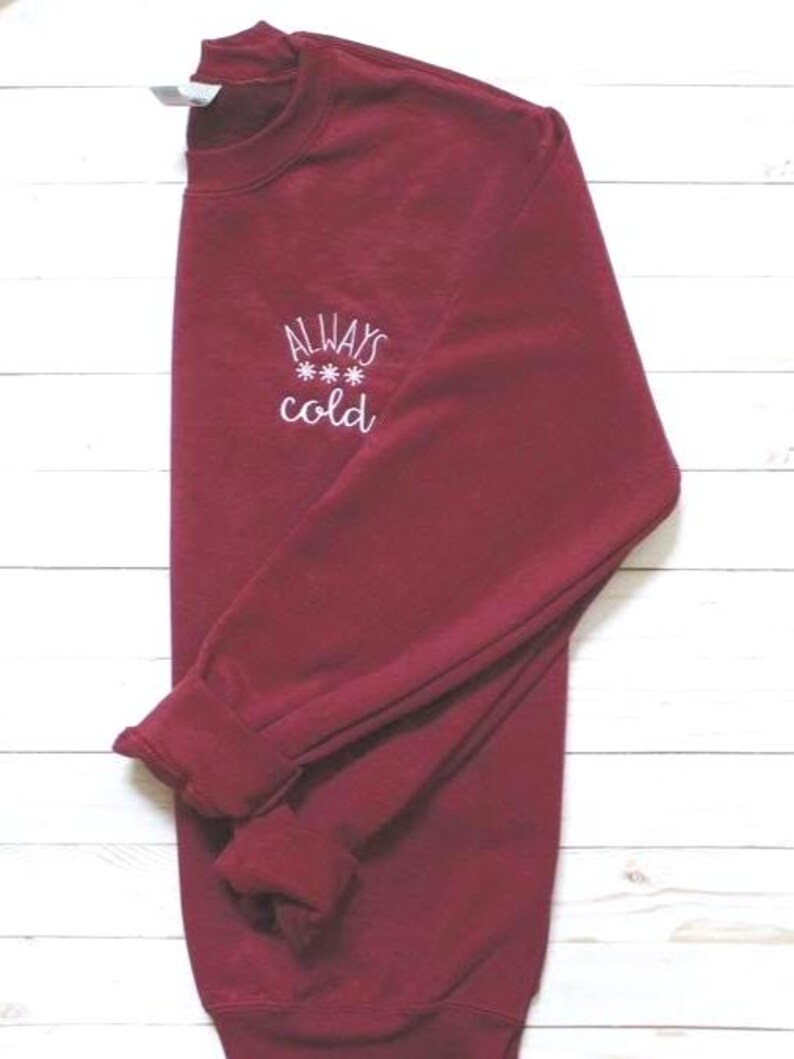 Pode incluir: Camisola de cor bord&ocirc; com texto bordado em branco que diz "ALWAYS *** cold".