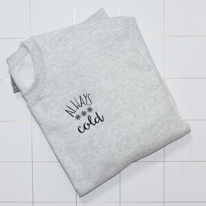 Pode incluir: Uma camisa de moletom cinza com o texto "ALWAYS *** cold" bordado na frente.