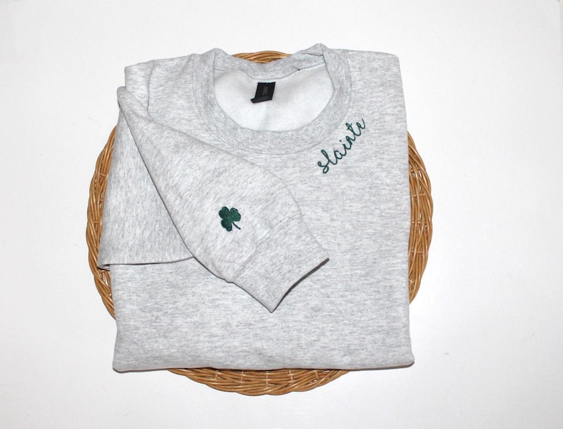 May include: A gray sweatshirt with a green shamrock embroidered on the sleeve and the word "slainte" embroidered on the front.