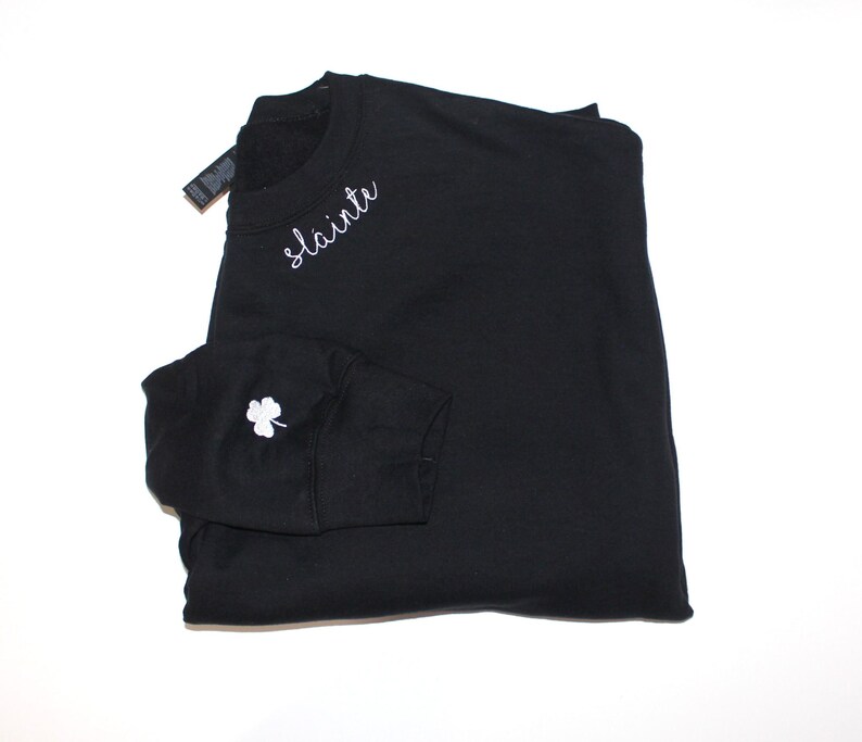 May include: Black sweatshirt with a white embroidered shamrock on the sleeve and the word "slainte" on the front.