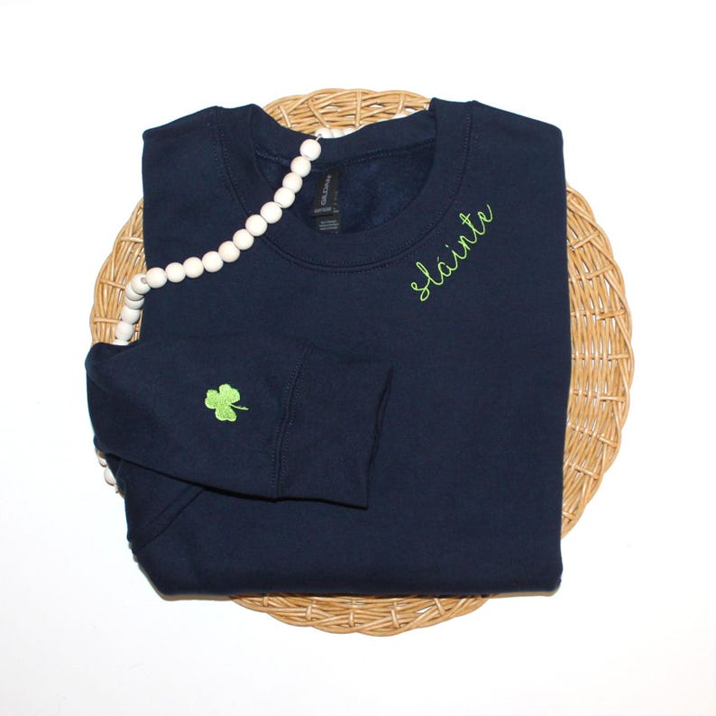 May include: A navy blue sweatshirt with a green shamrock on the sleeve and the word "slainte" embroidered on the right shoulder.