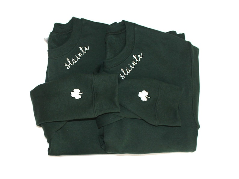 May include: Two dark green sweatshirts with white embroidered shamrocks and the word "Slainte" on the front.