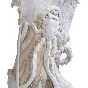 Puede incluir: Calcet&iacute;n de Navidad de fieltro blanco con una figura de Pap&aacute; Noel beige, adornada con cuentas y lentejuelas blancas y plateadas. El calcet&iacute;n tiene una etiqueta de fieltro blanco con el nombre "Amy" escrito en cursiva marr&oacute;n.