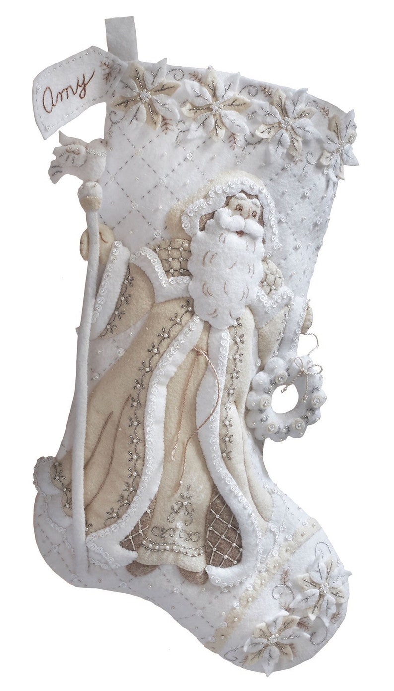 Puede incluir: Calcet&iacute;n de Navidad de fieltro blanco con una figura de Pap&aacute; Noel beige, adornada con cuentas y lentejuelas blancas y plateadas. El calcet&iacute;n tiene una etiqueta de fieltro blanco con el nombre "Amy" escrito en cursiva marr&oacute;n.