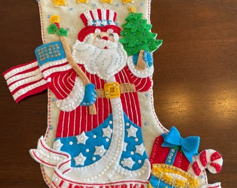 Calcetín navideño Bucilla terminado con el estampado “Santa Claus de Estrellas y Rayas”.