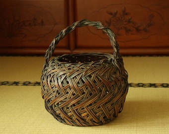 Cesta japonesa antigua de bambú para ikebana: tejido ajiro con maceta de agua.