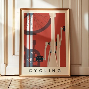 May include: Framed art print featuring a stylized bicycle illustration. The artwork has a red background with white and blue accents, and the word "CYCLING" is printed at the bottom in a bold, black font. The frame is gold.