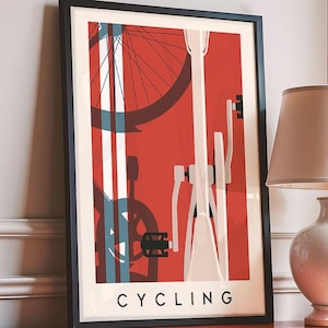 May include: A framed print with a cycling theme, set against a red backdrop with bicycle parts. The artwork is on a bright red cabinet, beside a white lamp with a beige lampshade. The word "CYCLING" is printed at the bottom of the artwork.