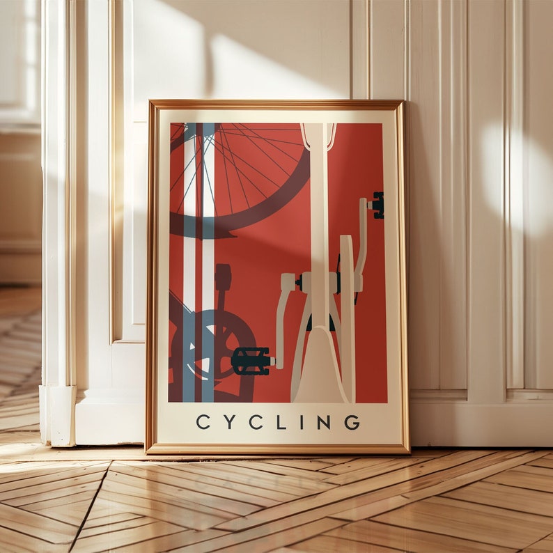 May include: Framed art print featuring a stylized bicycle illustration. The artwork has a red background with white and blue accents, and the word "CYCLING" is printed at the bottom in a bold, black font. The frame is gold.