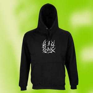 Könnte beinhalten: Ein schwarzer Kapuzenpullover mit einem weißen Grafikdruck auf der Brust, der "GAY PANIC" in einer stilisierten, scharfkantigen Schrift zeigt. Das Kleidungsstück verfügt über eine Kapuze mit Kordelzug, lange Ärmel und eine Kängurutasche.