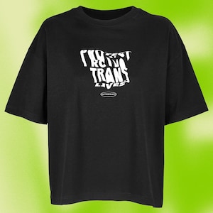 Könnte beinhalten: Schwarzes T-Shirt mit einem weißen Aufdruck, der in einer verzerrten Schriftart "Protect Trans Lives" lautet.