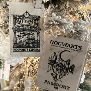 May include: Two white luggage tags with black text and images. The first tag features a black and white illustration of a train with the text "Platform 9 3/4 Kings Cross Station Hogwarts Express". The second tag features a black and white illustration of Hogwarts castle with the text "Hogwarts School of Witchcraft and Wizardry Passport".