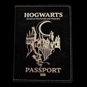 May include: Black leather passport holder with gold lettering that reads "HOGWARTS School of Witchcraft and Wizardry" and "PASSPORT". The holder features a gold silhouette of Hogwarts castle with a crescent moon.