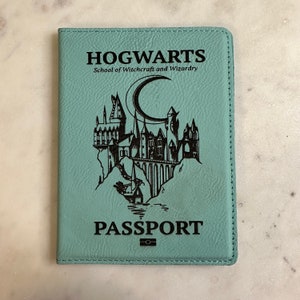 May include: A teal blue passport holder with the words "HOGWARTS School of Witchcraft and Wizardry" and a black silhouette of Hogwarts castle with a crescent moon above it. The words "PASSPORT" are printed below the castle.