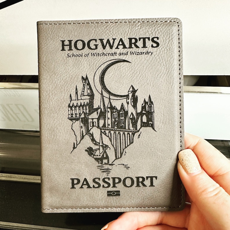May include: A gray leather passport holder with the Hogwarts School of Witchcraft and Wizardry logo and the word "PASSPORT" printed on it.
