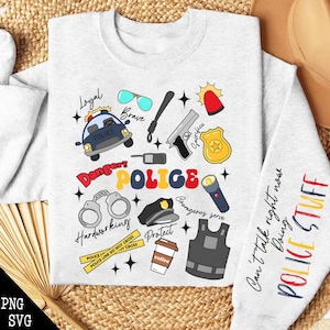 Op de afbeelding: Een lichtgrijs sweatshirt met een kleurrijk politie-thema. Het ontwerp bevat een politieauto, handboeien, een badge en het woord "POLICE" in grote, kleurrijke letters. De mouw leest "POLICE STUFF".