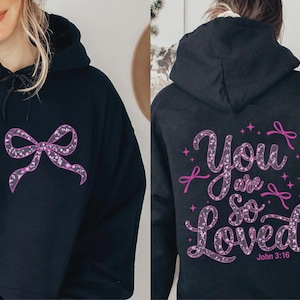 May include: Black hoodie with a pink glitter bow on the front and a pink glitter design that says "You are so loved" with the Bible verse John 3:16 on the back.