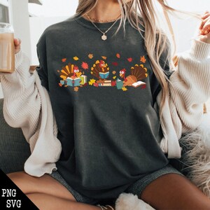 May include: A dark gray sweatshirt with a design of three turkeys reading books. The turkeys are surrounded by fall leaves and books.