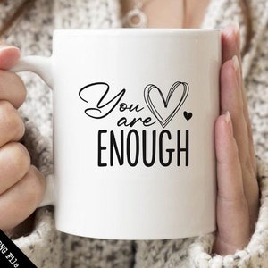 May include: White ceramic mug with a black design that says "You are enough" with a heart in the middle of the text.