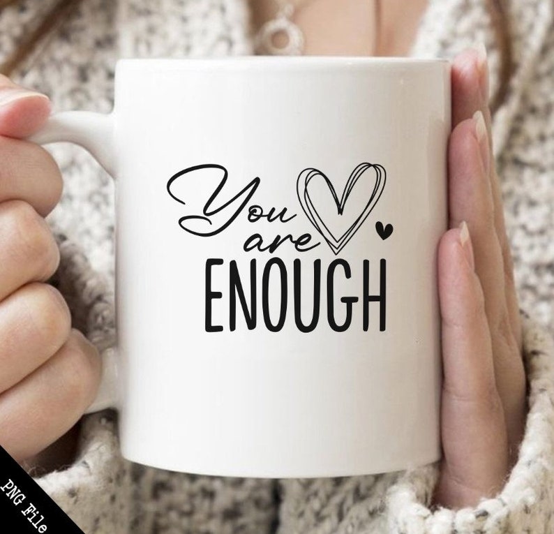 May include: White ceramic mug with a black design that says "You are enough" with a heart in the middle of the text.