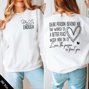 May include: White sweatshirt with a black graphic on the front that says "You are Enough" with a heart. The back of the sweatshirt has a black graphic that says "Dear person behind me the world is a better place with you in it. Love, the person in front you" with a heart.