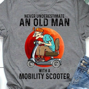 May include: Gray t-shirt with a graphic of an older person driving a mobility scooter with the text "Never underestimate an old man with a mobility scooter".