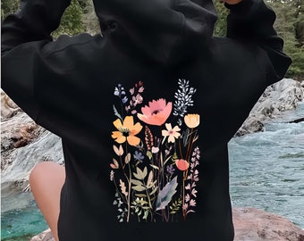 May include: Black hooded sweatshirt with a floral print on the back. The print features a variety of flowers in shades of pink, yellow, and orange, with green leaves and stems.