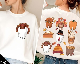 May include: White sweatshirt with a Thanksgiving-themed tooth design on the front. The back of the sweatshirt features multiple Thanksgiving-themed tooth designs, including a turkey, pumpkin, pie, and a coffee cup.