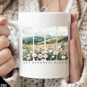Op de afbeelding: Witte keramische mok met een aquarelontwerp van een veld met madeliefjes en bergen. De tekst "Let Kindness Bloom" is op de mok gedrukt.