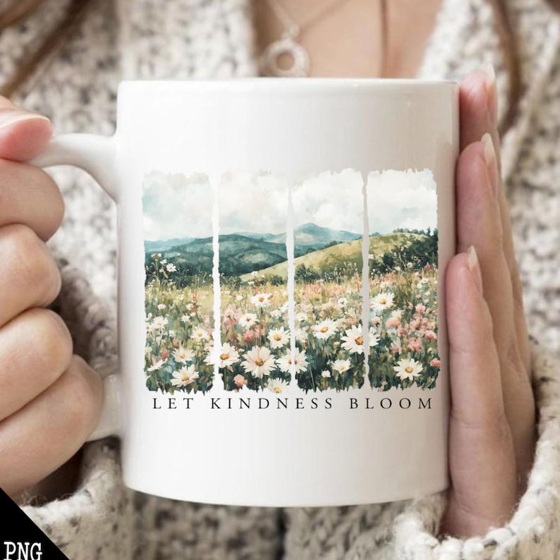 Op de afbeelding: Witte keramische mok met een aquarelontwerp van een veld met madeliefjes en bergen. De tekst "Let Kindness Bloom" is op de mok gedrukt.