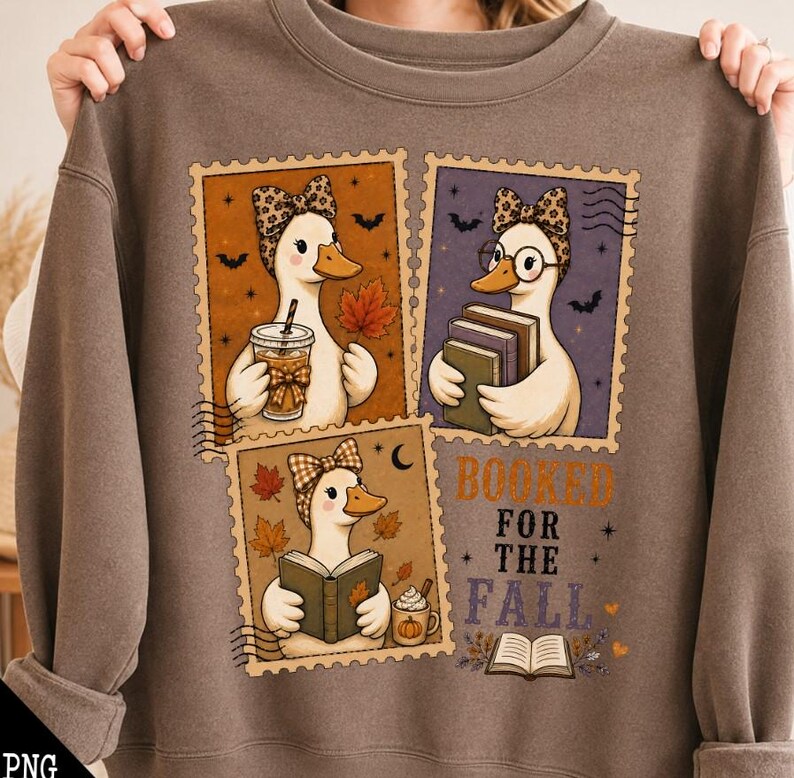 May include: A brown crewneck sweatshirt featuring a graphic print of three postage stamp-style illustrations of ducks. The ducks wear patterned headbands and are depicted holding books, a coffee cup, and a pumpkin mug. The text reads BOOKED FOR THE FALL.