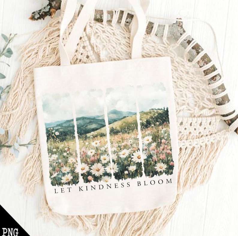 Op de afbeelding: Een witte tote bag met een aquarelontwerp van een bergketen en wilde bloemen. De tekst "Let Kindness Bloom" is op de tas gedrukt.