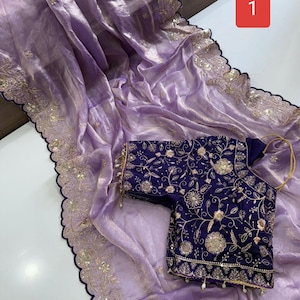 May include: A light purple sheer saree with a scalloped dark blue border featuring gold embroidery and sequins, paired with a dark blue blouse adorned with intricate gold floral embroidery, sequins, and small hanging beads at the hem.