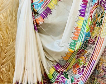 May include: White silk saree with colorful embroidered floral patterns. The saree has a wide border with intricate designs in shades of red, yellow, green, blue, and purple.