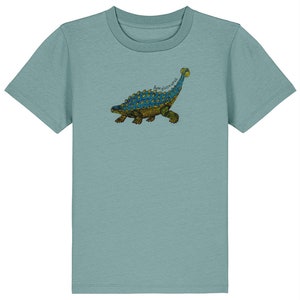 Könnte beinhalten: Ein hellblaues T-Shirt mit einem Aufdruck eines Ankylosaurus-Dinosauriers in Grün, Blau und Braun.