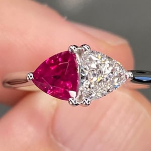 May include: A silver ring featuring a triangular ruby gemstone and a triangular diamond gemstone.