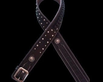 Peut inclure: Une ceinture en cuir noir avec des clous argentés et une boucle décorative. La ceinture a un design cousu et une boucle pour tenir des munitions.