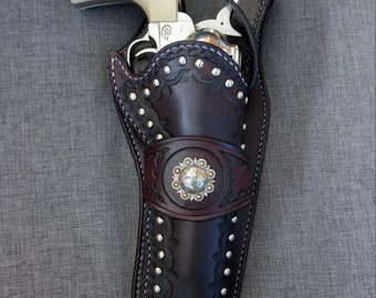 Peut inclure: Un étui en cuir marron avec des clous argentés et un concho argenté décoratif. Un revolver argenté est à l'intérieur de l'étui.