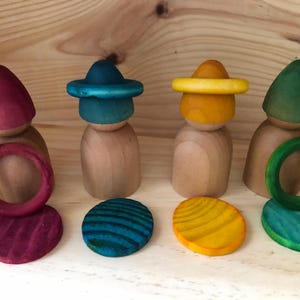 Peut inclure: Poup&eacute;es en bois avec chapeaux, anneaux et bases circulaires color&eacute;s. Les chapeaux sont rouges, turquoise, jaunes et verts. Les bases et les anneaux sont peints pour correspondre aux chapeaux. Jouets pour le jeu imaginatif.