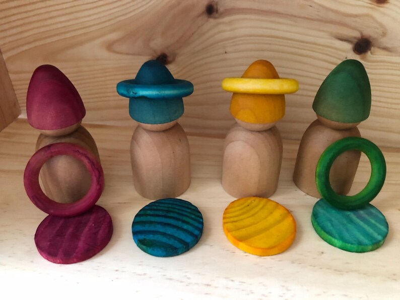 Peut inclure: Poup&eacute;es en bois avec chapeaux, anneaux et bases circulaires color&eacute;s. Les chapeaux sont rouges, turquoise, jaunes et verts. Les bases et les anneaux sont peints pour correspondre aux chapeaux. Jouets pour le jeu imaginatif.