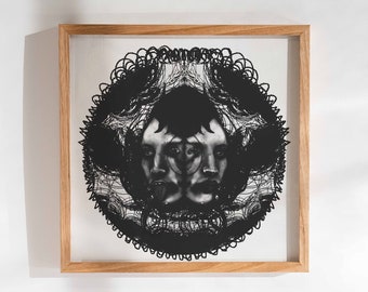 May include: A framed black and white print of a stylized face with intricate details. The face is surrounded by a circular design of swirling lines.