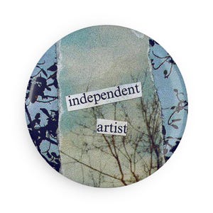 May include: A blue and white button with the words "independent artist" printed on it. The button features a collage of a tree branch and a sky background.