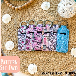 May include: A collection of patterned lip balm holders with key rings. The holders feature various designs, including ice cream, houses, and school supplies. The text "Pattern Set Two" and "Many patterns to choose from!" are visible.